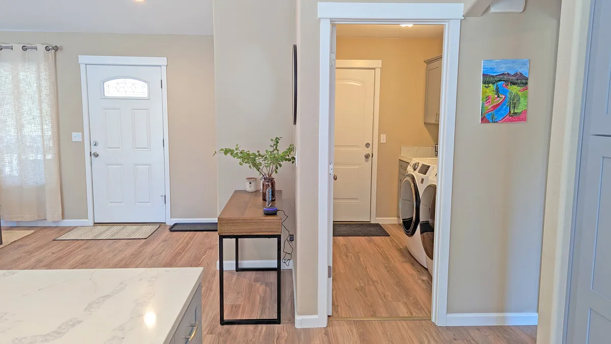 A welcoming view of the home's entryway, showcasing the front door, a cozy laundry area, and a console table with a decorative vase. This space is where the river pass is conveniently stored for guests' use.